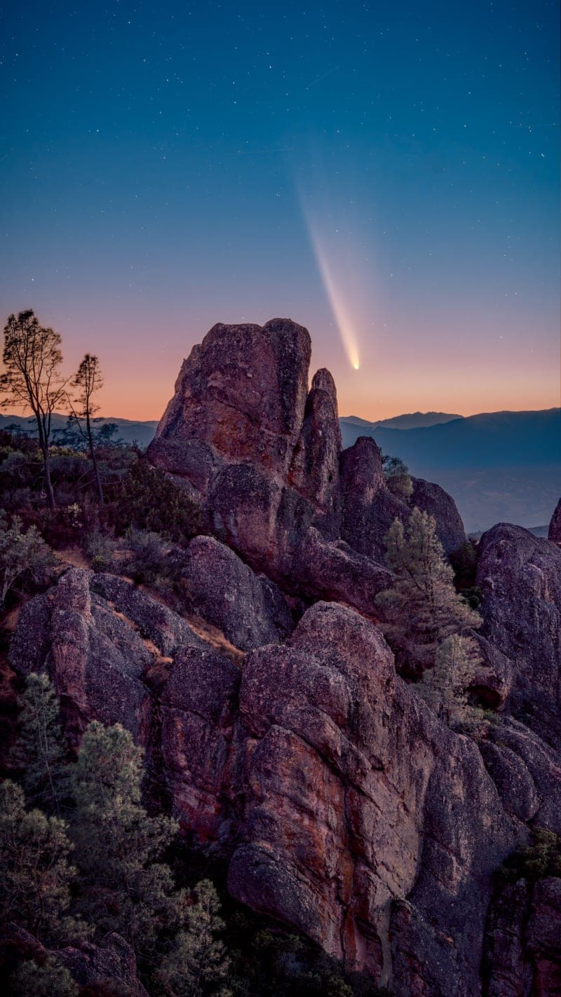Comet streaking over the Pinnacles rock formations under a starry sky